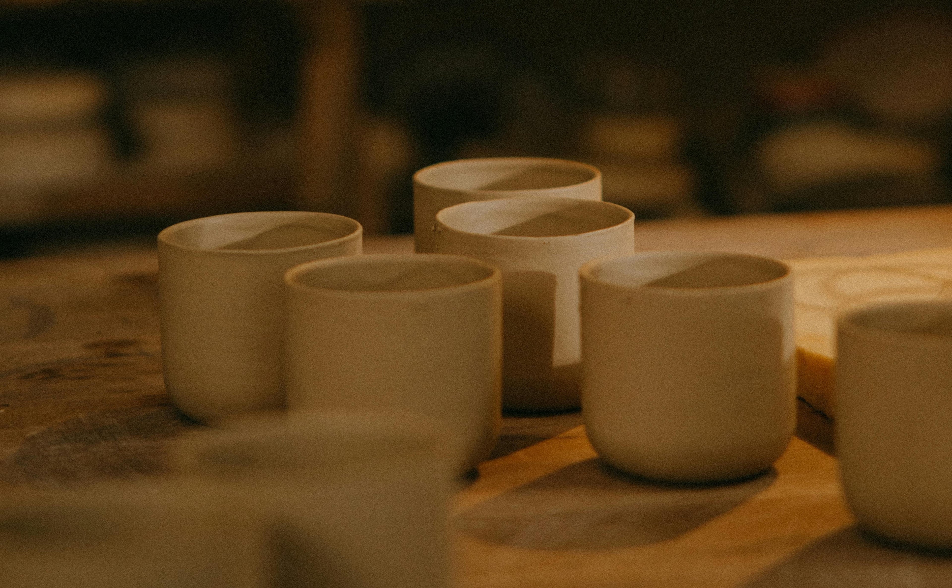 Muted, moody ceramics collection with raw clay cups in warm beige tones, perfect for vintage-inspired, dark interiors.
