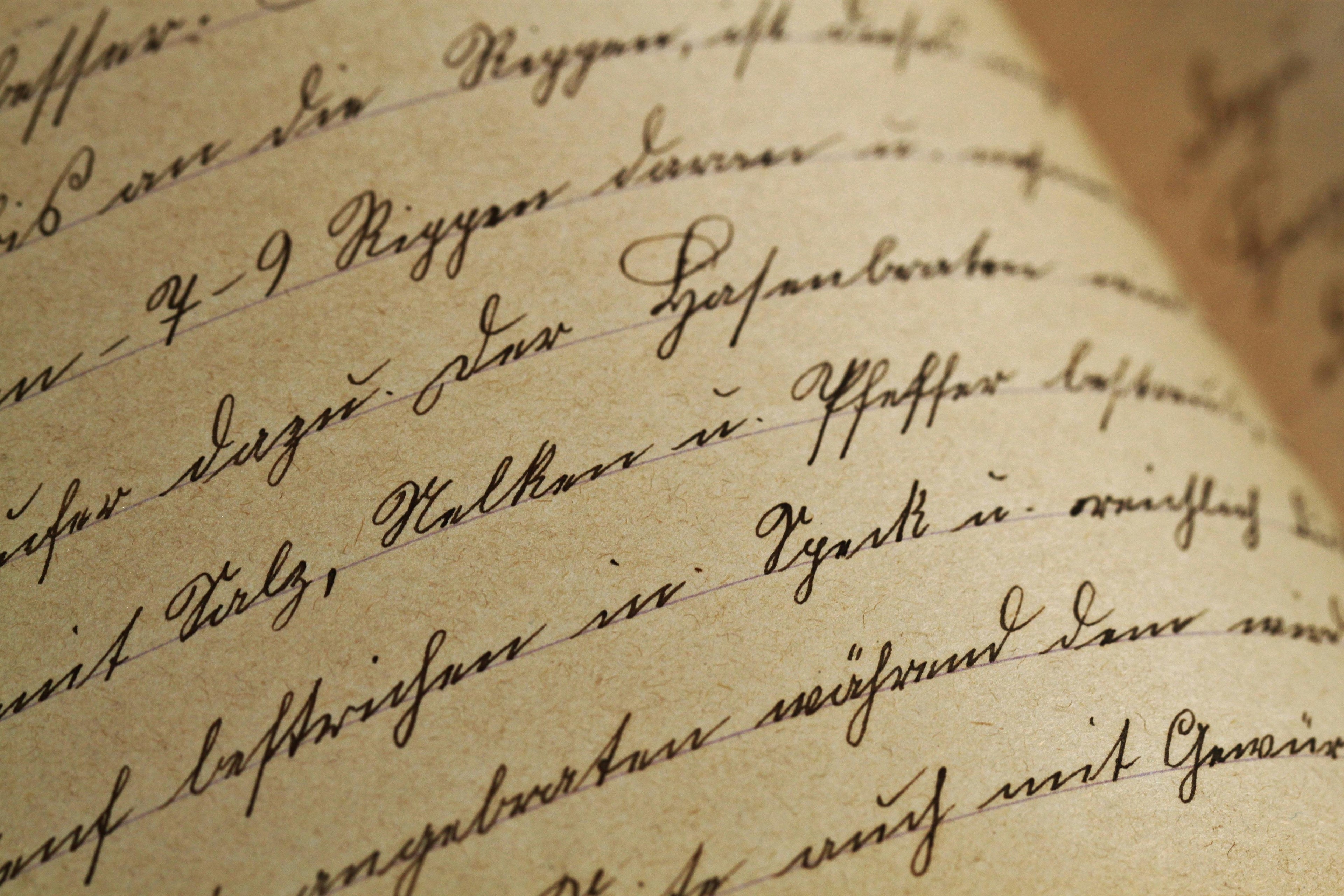 Close-up of antique script on parchment; sepia-toned, aged paper suggests historical documents, calligraphy, and vintage aesthetics.