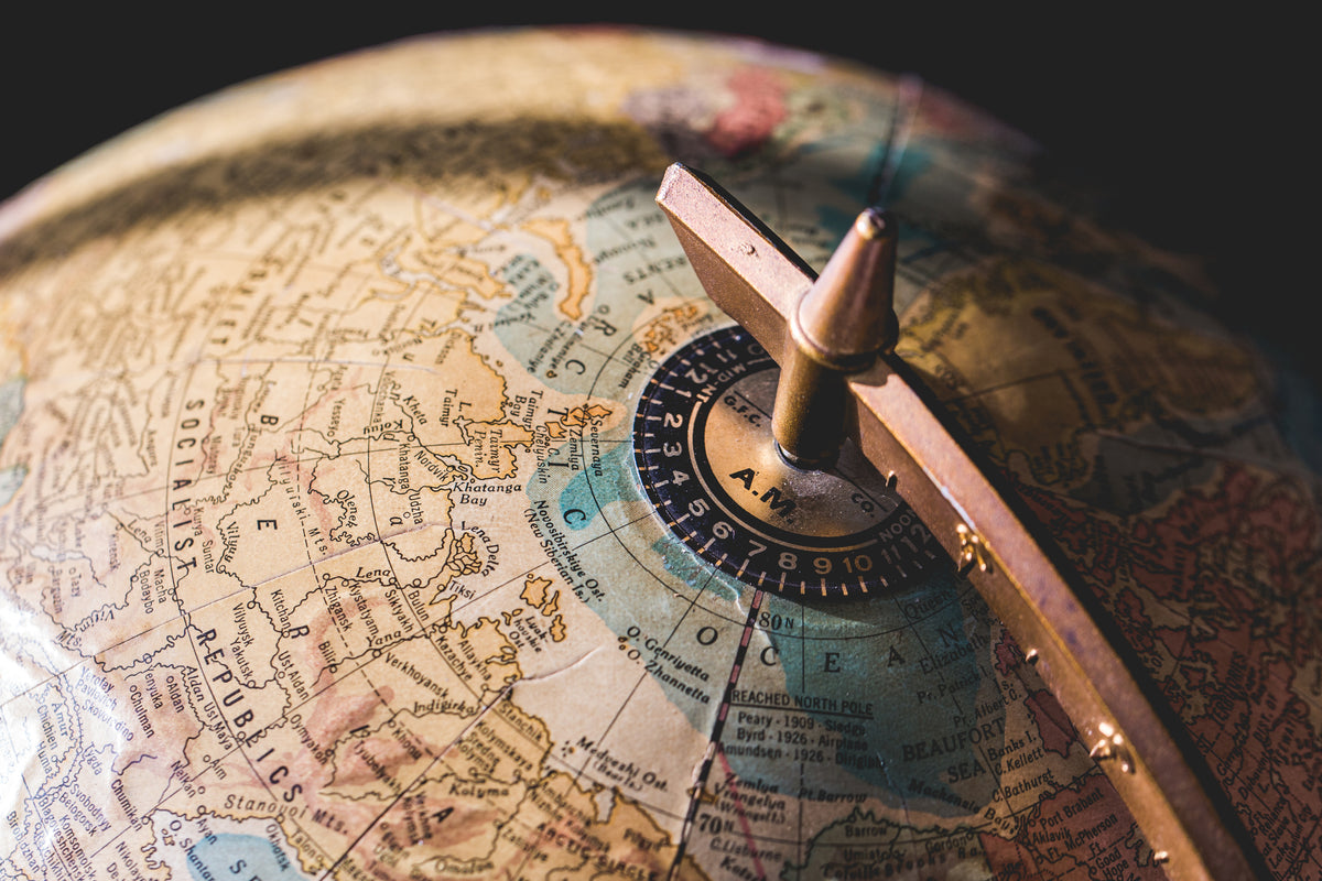 Close-up of an antique globe focusing on the Arctic region, showing map details with place names and a time dial.